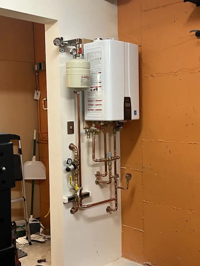 Plumbing technician inspecting water heater connections in Acme